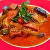 A plate of pepperonata sauce with eggplant, tomatoes with chicken and garnished with parsley