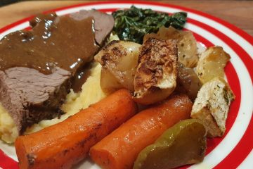 slow cooked roast beef on a plate with carrots mash potato and vegetables with gravey