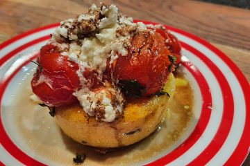 Griddled polenta on a plate topped with roasted tomatoes, goats cheese, drizzled with balsamic vinegar and olive oil