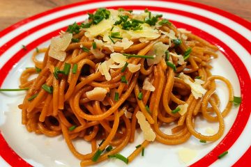 Vegemite spaghetti on a plate garnished with parmesan and chives